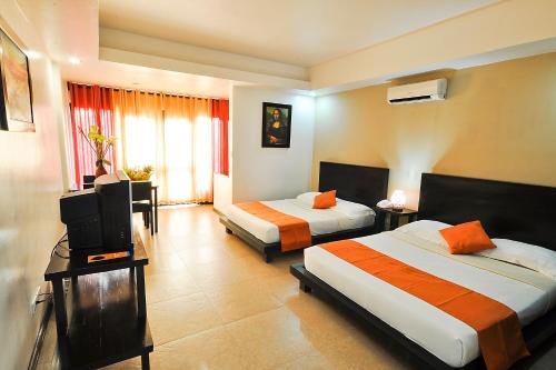 a hotel room with two beds and a television at Paradise Garden Hotel and Convention Center Boracay Powered by ASTON in Boracay