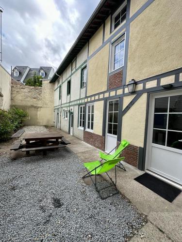 une chaise verte et une table de pique-nique devant le bâtiment dans l'établissement Petite maison place du marché, à Deauville