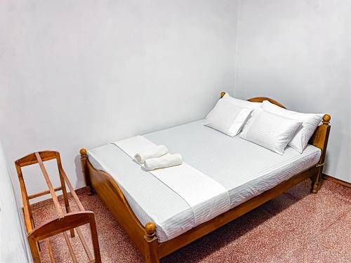 a bed with white sheets and a chair in a room at Wicks Backpacker's Lodge - Peaceful Quality stay, Walk to the Historic Galle Dutch Fort and the beach in Galle
