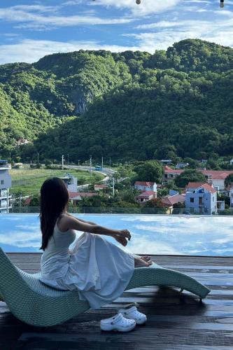 a woman sitting on a chair looking out of a window at Eden Hotel Cát Bà in Cat Ba