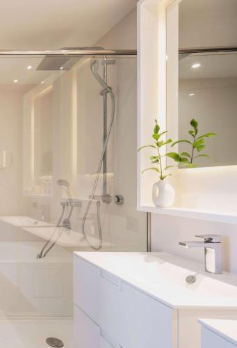 a white bathroom with a shower and a sink at Hotel Don Pepe Gran Meliá in Marbella