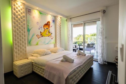 une chambre avec un lit avec un tableau sur le mur dans l'établissement Villa Reninca - Côte D'Azur, à Saint-Tropez