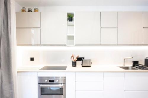 a white kitchen with white cabinets and a sink at Studio cosy dans chalet in Abriès