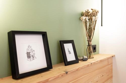two framed pictures sitting on a wooden shelf with flowers at Studio cosy dans chalet in Abriès