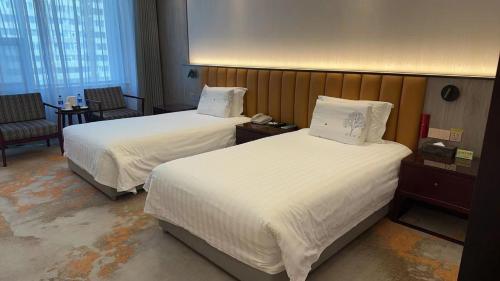 a hotel room with two beds and a chair at Beijing Jingyi Hotel in Beijing