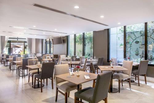 a dining room with tables and chairs and windows at Meliá Paulista in Sao Paulo