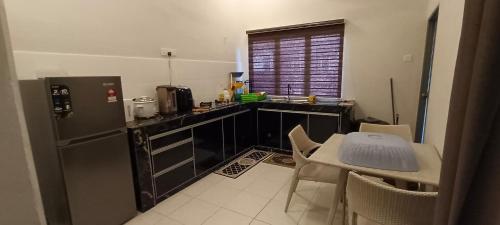 Una cocina con refrigerador y una mesa con sillas. en Homestay Bilal, en Kuantan