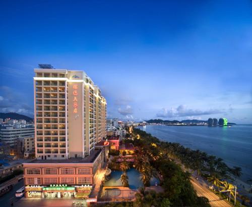 a tall building next to the ocean at night at Shengyi Holiday Villa Hotel in Sanya