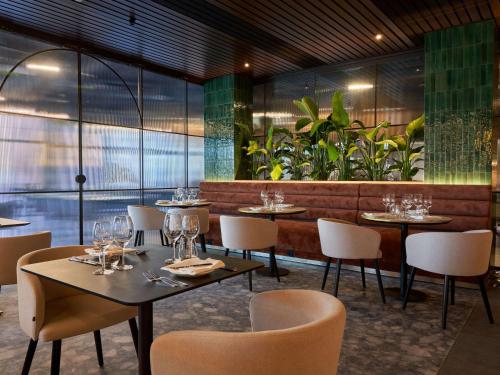 a restaurant with tables and chairs and plants at Mövenpick Resort & Spa Karpacz in Karpacz