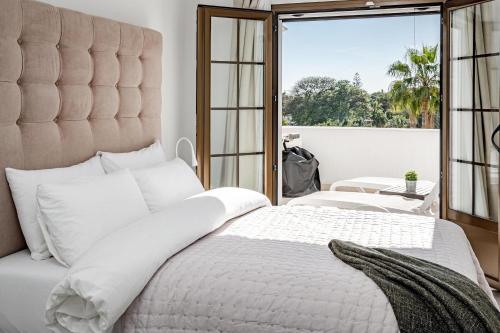 a bedroom with a large white bed with a large window at AB4 - vacation home, Marbella by Roomservices in Marbella