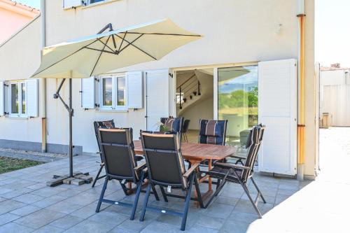 a table with chairs and an umbrella on a patio at Holiday home Viva in Gajac