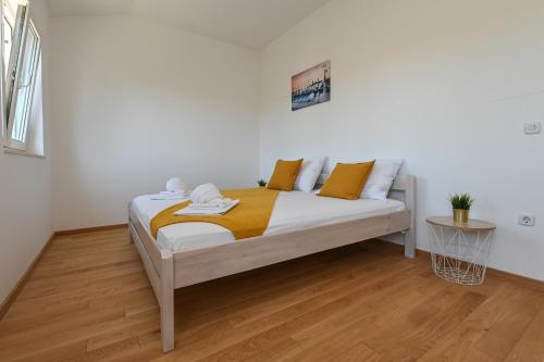 a bed with yellow and white pillows in a room at Holiday home Viva in Gajac