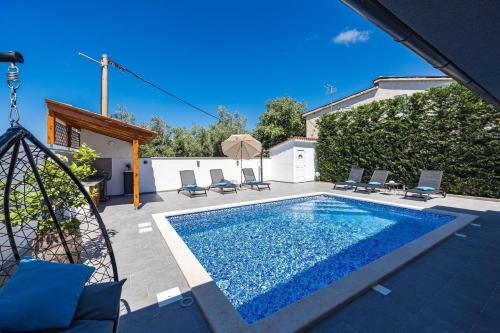 a swimming pool in a backyard with chairs around it at Villa Bavaria in Galižana