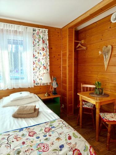 a bedroom with a bed and a table and a window at Leonówka Bieszczady in Cisna
