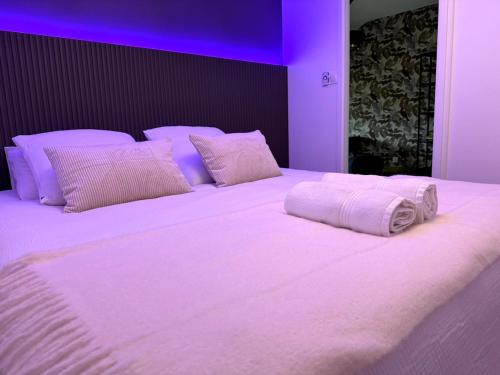 un grand lit blanc avec des lumières violettes dessus dans l'établissement ღ Bubble Loft - Bain Balnéo, spacieux en centre ville, à Nantes