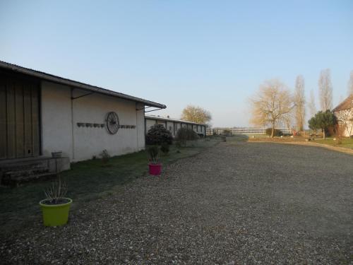 a gravel driveway next to a building with potted plants at Ferme les Rousseaux in La Belliole
