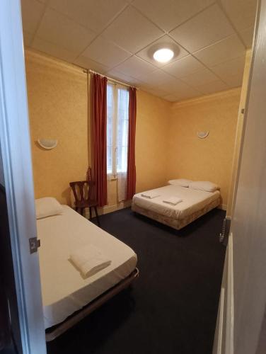 a hotel room with two beds and a window at Chambre chez Marie et Didier 1 minute à pied du sanctuaire de Lourdes in Lourdes
