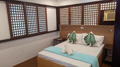 a bedroom with a bed with two pillows and windows at Aquaventure Reef Club in Mabini