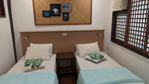 two twin beds in a small room with a window at Aquaventure Reef Club in Mabini