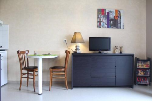 Il comprend un salon doté d'une télévision et d'une table avec des chaises. dans l'établissement Appt Studio LA ROCHELLE - LR040-311, à La Rochelle