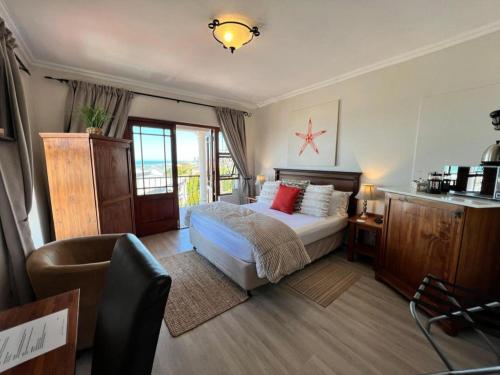 a bedroom with a bed and a chair in it at Sea Whisper Guest House in Jeffreys Bay
