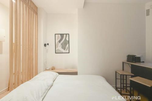 une chambre avec un lit blanc dans une pièce dans l'établissement Flexliving - Studio - La Fayette, à Paris