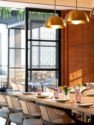 a long table in a restaurant with chairs and lights at Pullman Chennai Anna Salai - Premium Brand By Accor in Chennai