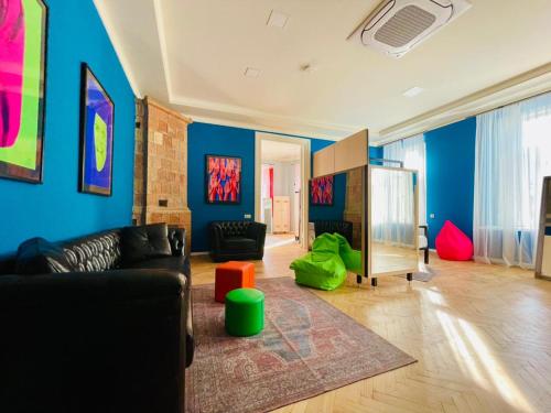 a living room with blue walls and a black couch at Communa Good Vibes in Tbilisi City