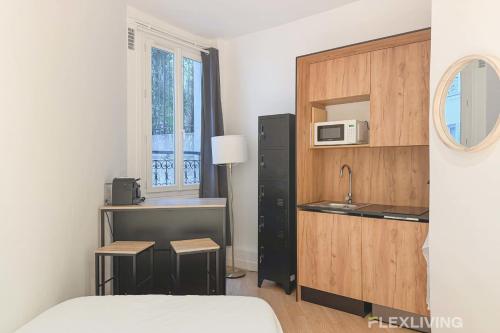 Cette petite chambre d'hôtel dispose d'une cuisine et d'un lit. dans l'établissement Flexliving - Studio - La Fayette, à Paris