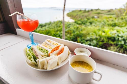 a plate of sandwiches on a table with a drink at Coral Sea Villa OKINAWA MIYAKOJIMA in Miyako-jima