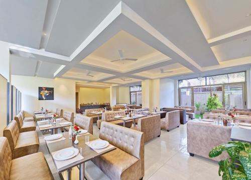a restaurant with tables and chairs and windows at Shivsagar Resort & Spa in Mahabaleshwar