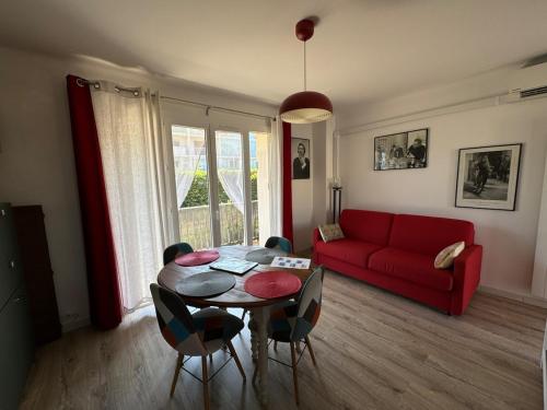 un salon avec une table et un canapé rouge dans l'établissement T2-4 pers-terrasse - 200m mer, à Six-Fours-les-Plages