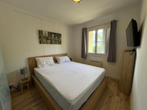une chambre avec un lit avec des draps blancs et une fenêtre dans l'établissement T2-4 pers-terrasse - 200m mer, à Six-Fours-les-Plages