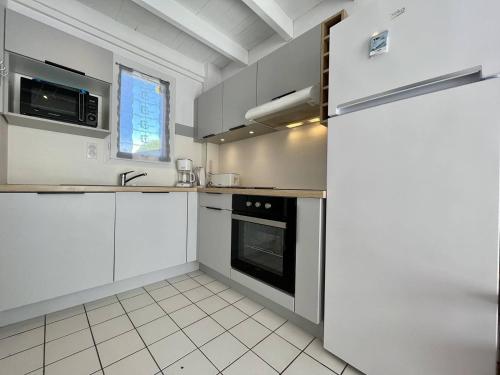une cuisine avec des armoires blanches et une cuisinière dans l'établissement Maison 4 pièces 6 couchages Saint Pierre d'Oléron SPO000-122, à Saint-Pierre-dʼOléron
