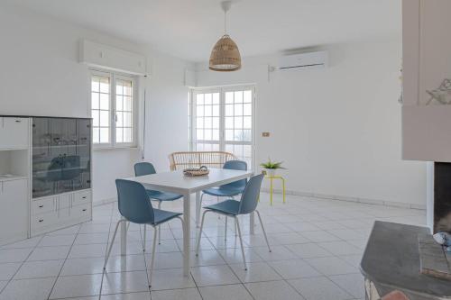 a white kitchen with a white table and blue chairs at Ferrante - YourPlace Abruzzo in Fossacesia