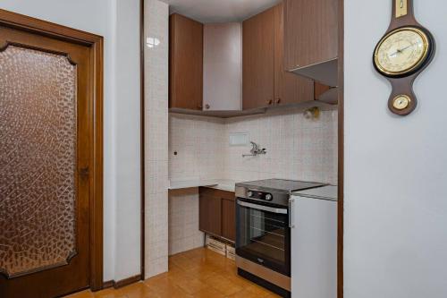 een keuken met een klok aan de muur en een fornuis bij Via Roma 44 - YourPlace Abruzzo in Roccaraso