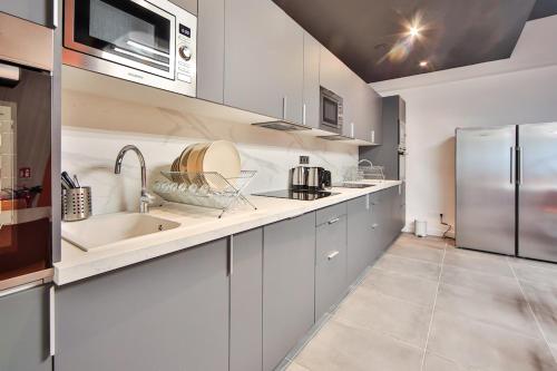 a kitchen with white cabinets and a stainless steel refrigerator at 04 Studio Charenton Fitness Cinema in Charenton-le-Pont
