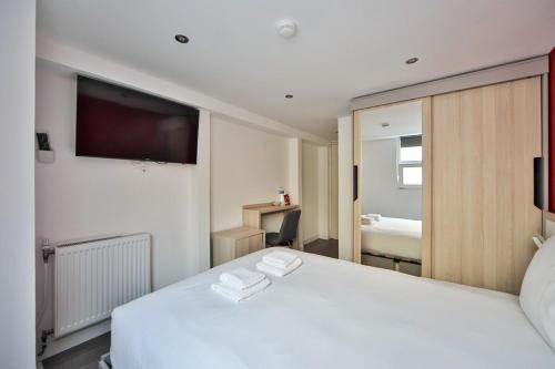 a bedroom with a white bed and a television at 04 Studio Charenton Fitness Cinema in Charenton-le-Pont