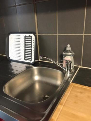un évier en acier inoxydable dans une cuisine avec un distributeur de savon dans l'établissement Le St Romain Proche Bugey & Lyon, à Saint-Romain-de-Jalionas