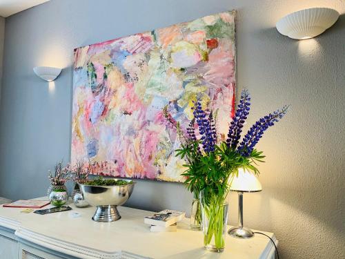 un dipinto su un muro con un vaso di fiori su una scrivania di Bärliner Hotel a Erfurt