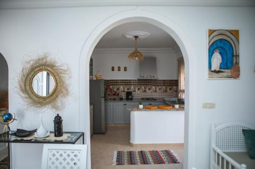a kitchen with an archway leading into a living room at Villa Bianca - à 10 min de la plage in Fafou
