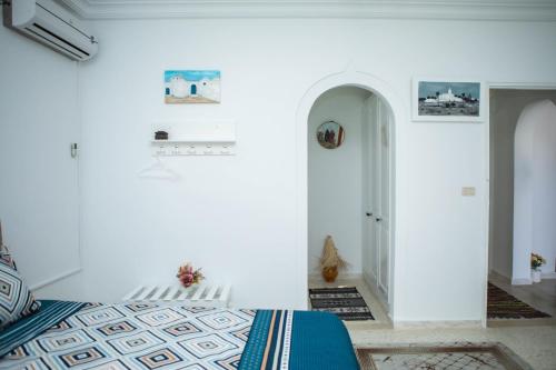a bedroom with white walls and a bed with a blue blanket at Villa Bianca - à 10 min de la plage in Fafou