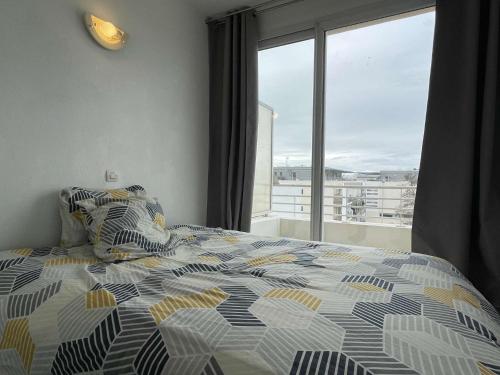 une chambre avec un lit et une grande fenêtre dans l'établissement Appt 3 pièces LA ROCHELLE - LR030-D223, à La Rochelle