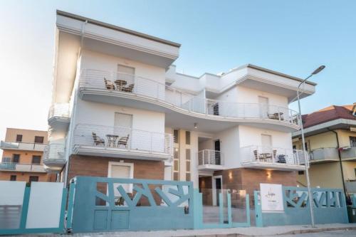 an apartment building with balconies and a blue fence at Residence Near The Sea - Abruzzo in Martinsicuro