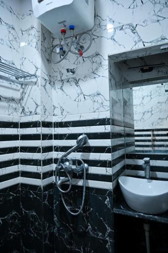 a black and white bathroom with a sink and a mirror at Hotel Hari Gopal in Varanasi