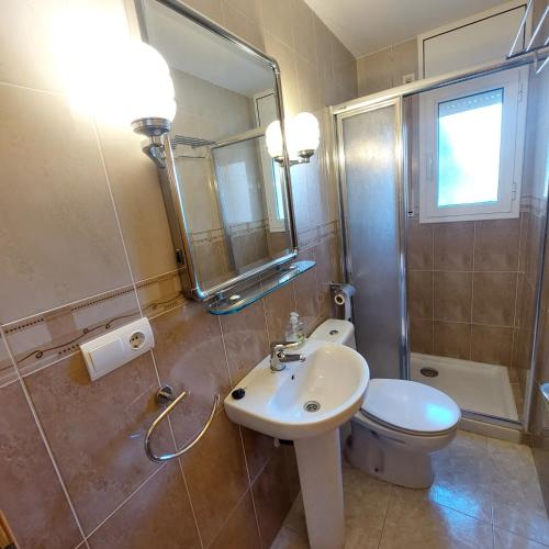 a bathroom with a sink and a toilet and a mirror at Villa Naomi in Les tres Cales