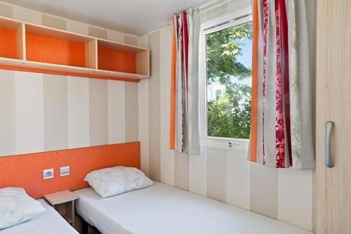 une petite chambre avec deux lits et une fenêtre dans l'établissement Camping Le Bois de Pleuven, à Saint-Yvy