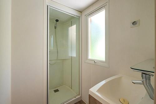 une salle de bain blanche avec une douche et un lavabo dans l'établissement Camping Le Bois de Pleuven, à Saint-Yvy