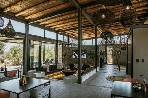 an open living room with a fireplace and large windows at Umoya Safari Lodge in Matlhagame
