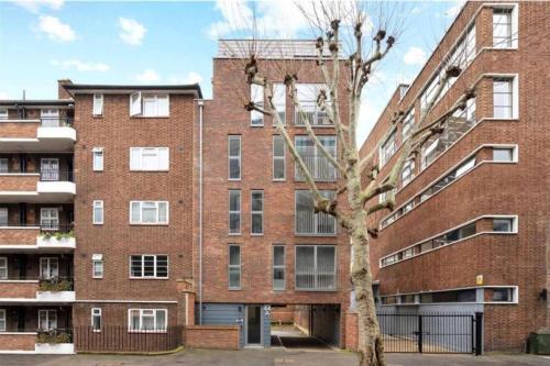 a red brick building with a tree in front of it at Split Level 3 Bedroom Top Floor Flat in London